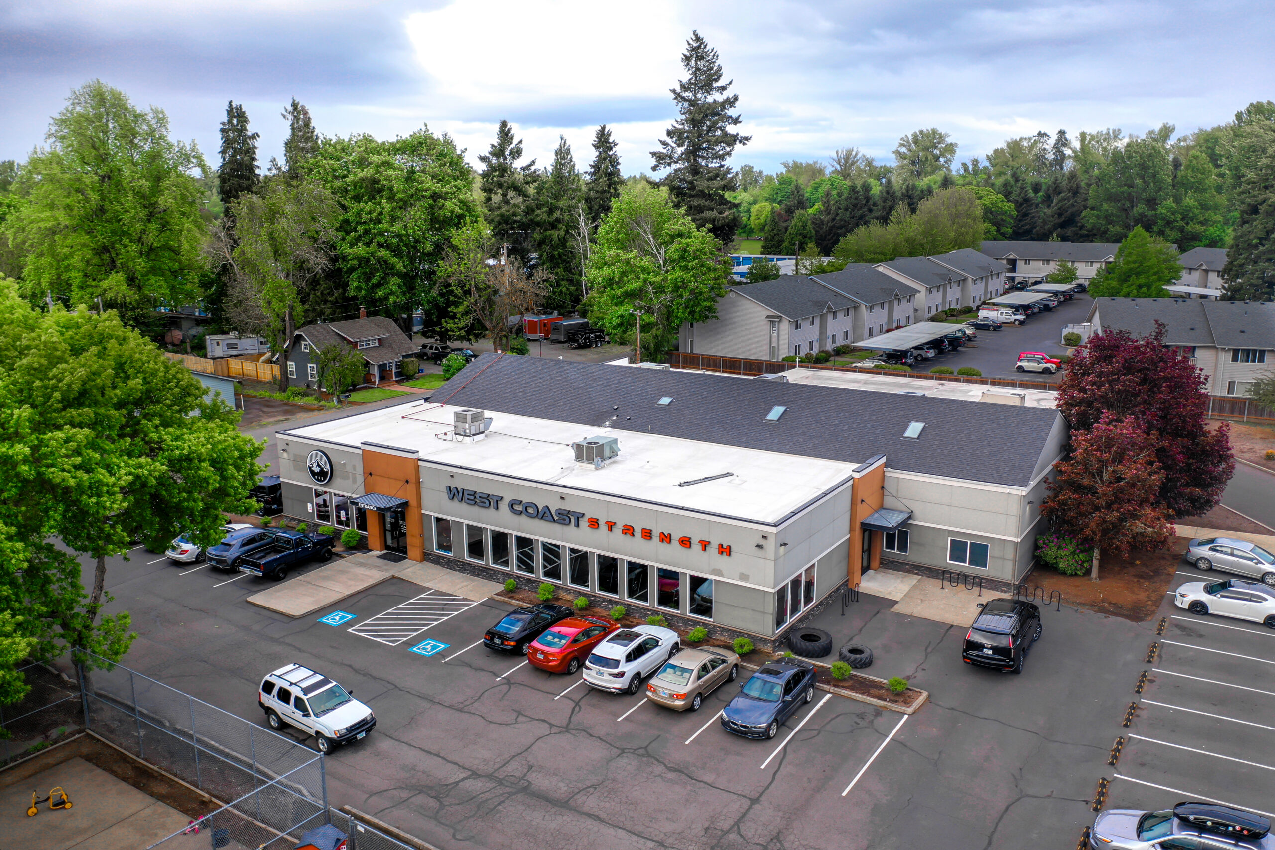 Aerial view of the West Coast Strength building exterior and parking lot surrounded by trees