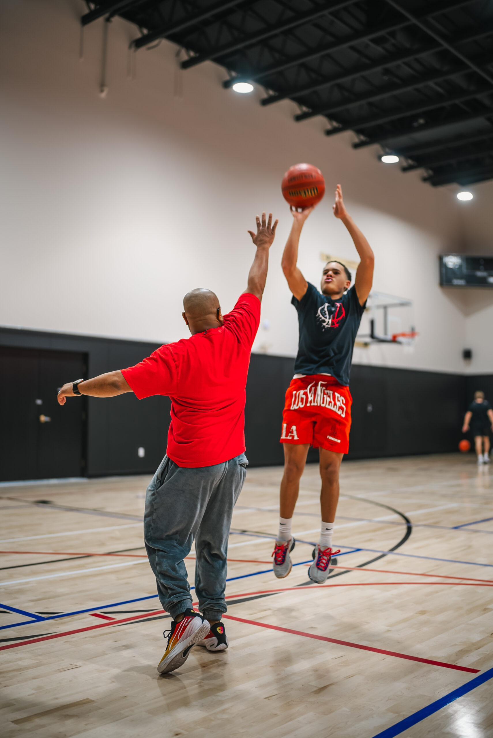 One player shoots a jump shot over a defender during a basketball game on the indoor court